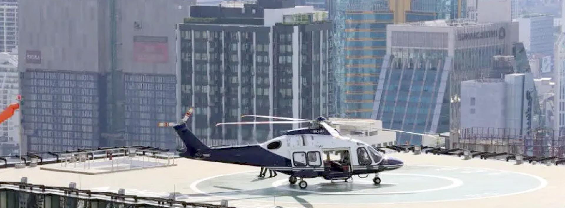 Helicóptero AgustaWestland en helipuerta sobre rascacielos en skyline urbano — movilidad ejecutiva de élite