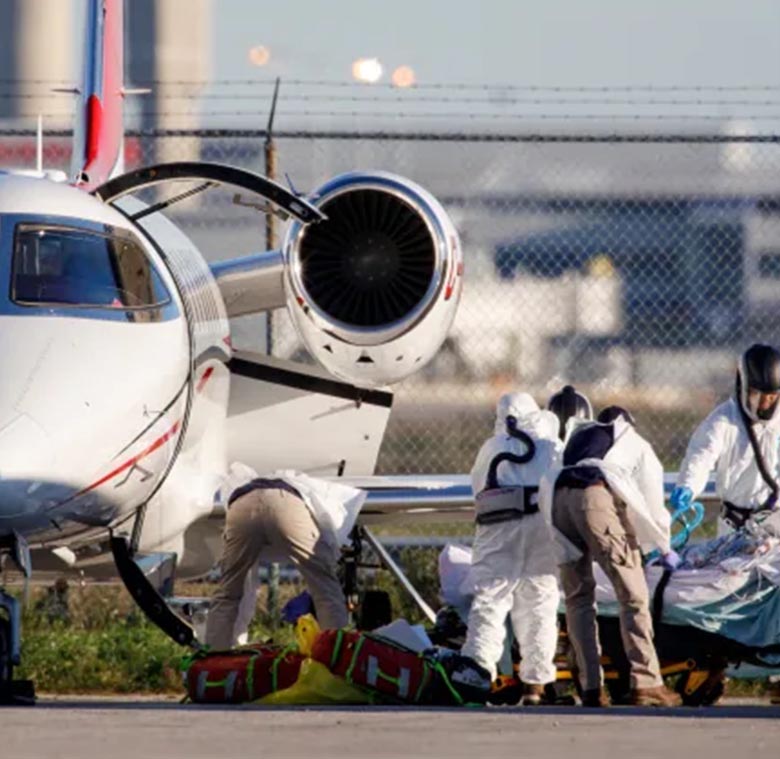 Equipo médico trasladando a un paciente en camilla hacia un jet sanitario